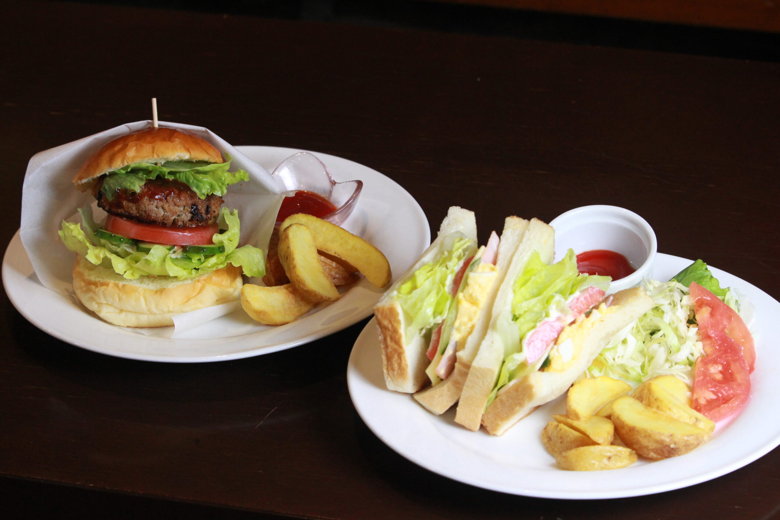 焼きたてパンの盛り合わせを収めたバスケット。メロンパンやクリームパンなどのパンの奥にはフルーツケーキや動物モチーフのデザートが飾られている